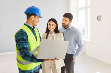 Aile bireyleri ev yenileme projesinin planlarını inceleyen bir müteahhit veya müteahhitle görüşüyor. Birlikte inşaat planlarını gözden geçirip projenin önemli detaylarını tartışıyorlar..