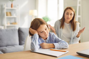 Öfkeli anne, evdeki ödev sırasında öğrenci oğlunu azarlıyor. Çevrimiçi öğrenme zorluklarını, ebeveynliği ve eğitimde sabrın önemini vurgulayan bir aile kavgası.