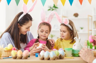 Paskalya için dekorasyon, ailede bahar tatili geleneği için yumurta süsleme, tavşanlı tavşan kulaklı çocuklarla anne aktivitesi tatil partisi dekorasyonu, festival atmosferi.