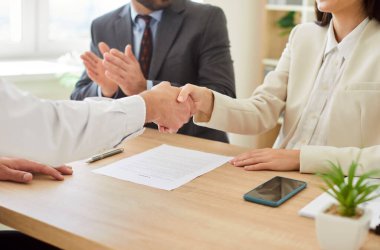 İş adamlarının bir anlaşmayı sağlamlaştırırken ya da ofiste bir toplantı sırasında el sıkışırken yakın plan çekimleri, takım çalışması, ortaklık ve profesyonel toplum dinamiklerini vurguluyor.