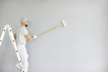 Boya ya da inşaat işçisi duvar boyası, profesyonel servis çalışanı koruyucu beyaz üniforma, hazırlık, boya fırçası ile boya, kaplama