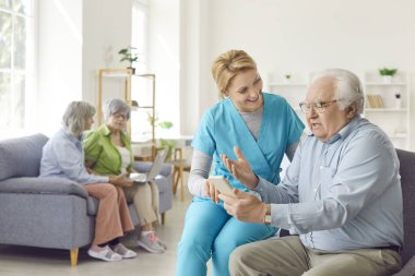 Kıdemli yaşlı adam ve yardımsever hemşire, yaşlı doktor, erkek bakımevinde ikamet eden kişi için telefon aramasına yardım eden yaşlı doktor, hasta ziyaretinde bulunan kadın doktor,