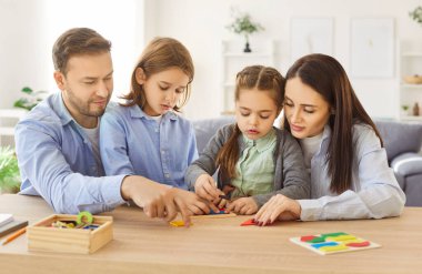 Mutlu bir aile oyunu oynuyoruz, ebeveynler ve çocuklar oyundan zevk alıyor, masa başında parçaları birleştiriyor, boş vakitlerde eğleniyor, evde eğleniyor, mantıklı ve iyi motor beceriler geliştiriyor, görevleri çözüyor,
