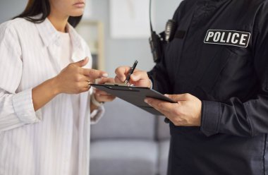 Erkek polis memuru kadın tanıkla ya da ev soygunu kurbanıyla görüşüyor. Üniformalı bir adamın genç bir kadına olay hakkında sorular sorarken çekilmiş bir fotoğrafı. Suç soruşturması kavramı