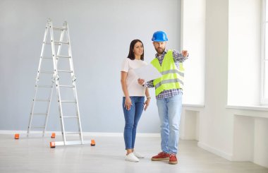 İşçi ve kadın müşteri bir tartışma içindeler, birlikte bir ev yenileme planlıyorlar. Brifingde inşaat detaylarını özetlemek ve süreç üzerinde işbirliği yapmak için bir plan kullanıyorlar..