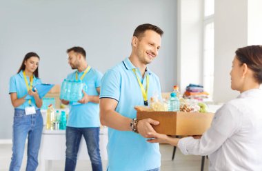 Hayır kurumunda çalışan ve hayır kurumunda bedava yiyecek bağışlayan genç ve neşeli bir erkek gönüllü portresi. Kötü kavram için insani yardım, gönüllü yardım ve sosyal yardım.