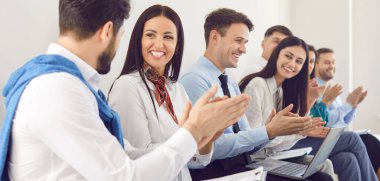 Mutlu genç adaylar, alkışlayan çeşitli çalışanlar, alkışlayan eller, tezahürat yapan akıl hocası koçu, sırada oturan, kurumsal toplantıda modern ofis, brifing veya atölye, iş başarısını kutlayan