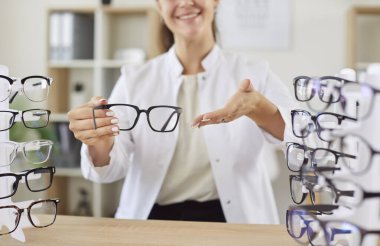 Gülümseyen gözlükçünün görüntüyü iyileştirmek için yeni gözlük vermesi. Optik mağazada gözlük gösteren pozitif göz doktoru hastaya gözlük seçmesinde yardım etmeye hazır. Göz sağlığı kavramı.