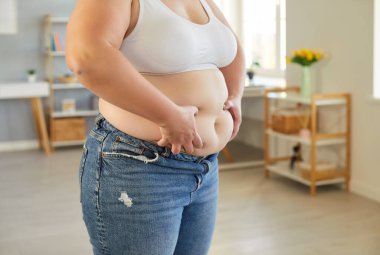 Tanınmayacak kadar şişman, sutyen ve kotlu şişman kadının kapalı bir yerde dikilip yağlı, çıplak karnını ellediği sahneler. Obezite, sağlık sorunları, kilo kaybı konsepti