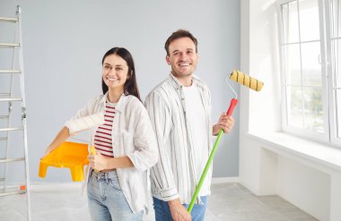 Genç bir çift, yeni aile planlama iç tasarımı, mutlu ressamlar veya inşaat işçileri boya fırçasıyla duvarları boyuyorlar, arkadaş canlısı servis ekibi odayı bitiriyor, tamirat işini bitiriyor.