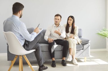 Genç bir çiftin portresi, erkek aile psikologu ile oturup terapi sırasında evlilik sorunları hakkında konuşuyor. Ruh sağlığı, psikoterapi ve ilişkiler kavramı