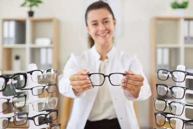 Pozitif kadın göz doktoru, optometri ve göz bakımını temsil eden gözlük tutuyor. Doktor optometrist, göz sağlığı için göz hekimliği ve uzmanlık hizmetleri sunmaktadır..