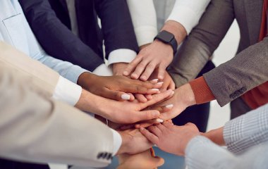 Kurumsal takım çalışması ve birlik. İş dünyasında birlik, çeşitlilik ve işbirliğini sembolize eden katlanmış eller. Farklı etnik gruplara mensup iş arkadaşlarının ellerini birleştirin..