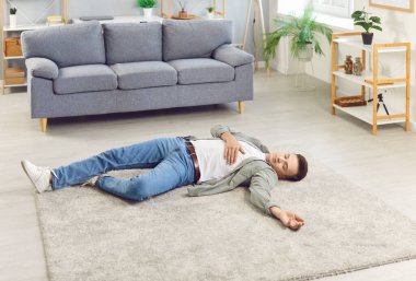 Bilinci yerinde olmayan genç bir adam evde kalp krizi geçirmiş ya da sağlık sorunları yaşıyor. Erkek kişi içeride bayılmış. Sağlık, tıp ve ilk yardım kavramı.