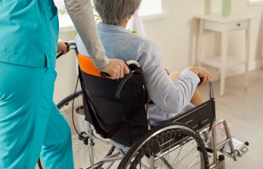 Klinikte hemşire tarafından tekerlekli sandalyedeki tanınmayan yaşlı kadının ciddi yaralanma sonrası tedavi ve rehabilitasyona uğradığı görüntüler. Bakım konsepti