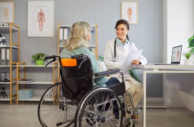 Tekerlekli sandalyedeki yaşlı kadın hasta bir doktor ya da hemşireyle tıbbi danışma için kliniğe gidiyor. Ziyaret sırasında yardım, sağlık yardımı ve profesyonel destek alma.