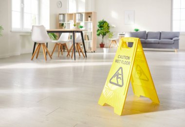 Temizlik ya da temizlik seansı sırasında evin zeminine sarı uyarı levhası asılmış. İşaret, güvenlik uyarısı olarak görev yapar. İhtiyatı vurgular ve olası tehlikelere karşı uyarır..