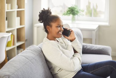 Genç Afrikalı Amerikalı kadın telefonda konuşuyor, cep telefonu tutan mutlu kız arıyor, cep telefonuyla konuşuyor, cep telefonuyla hoş sohbetler yapıyor, yemek sipariş ediyor, gevşemiş sohbet ediyor. 