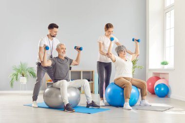 Rehabilitasyon merkezindeki genç antrenörler yaşlı bir çifte kaslarını düzeltmeleri için yardım ediyor. Yaşlı bir çift tıbbi bakım alır. Konsept fizyoterapi tedavisi, fizik tedavi