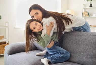 Anne-kız kaynaşıyor, sevimli küçük kız kucaklaşıyor, heyecanlı genç anne, bebek bakıcısı, sevgi ve şefkat gösteriyor, komik küçük anaokulu kızı evde gülüyor,