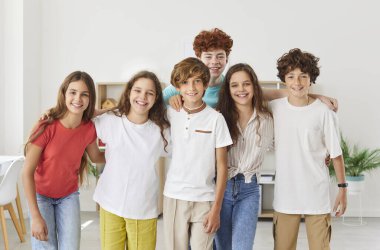 Genç çocuklar grup halinde kızlar ve oğlanlar içeride yan yana duruyorlar. Gülümseyen bir okul öğrencisinin portresi. Kameraya bakıp gülümseyen çocuklar. Sınıfta duruyorlar..