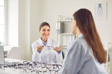 Optisyen, gözlük satan, göz doktoru, klinikte gülümseyen kadın doktor, müşterinin doğru gözlük, tıbbi görüş hizmeti, görme sorunları çözme, test, yeni gözlük reçetesi