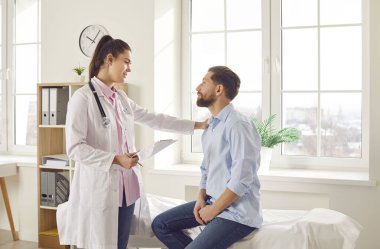 Kadın doktor erkek hastaya danışmanlık yapıyor, omuz omuza, laboratuvar sonuçlarını paylaşıyor, tıbbi kayıtları var. Tedavi için kliniğe gelen adam, tedavi planını tartışıyor, teşhis ve prosedür hakkında bilgi veriyor