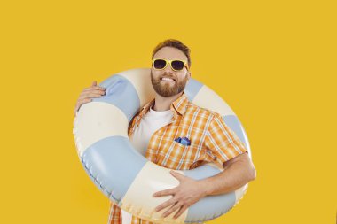 Yaz hazır. Sarı arka planda büyük mavi beyaz şişme bir can simidi tutan neşeli bir adamın portresi. Güneş gözlüklü beyaz sakallı adam şişme yüzme yüzüğü tutuyor ve kameraya gülümsüyor.