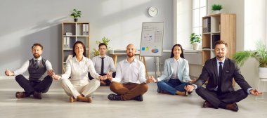 Huzurlu genç iş adamları meditasyon yapıyor ve Lotus 'ta yerde gözleri kapalı bir şekilde dinleniyorlar. Bir grup şirket çalışanı bir işe ara verirken egzersiz yapıyor. Pankart.