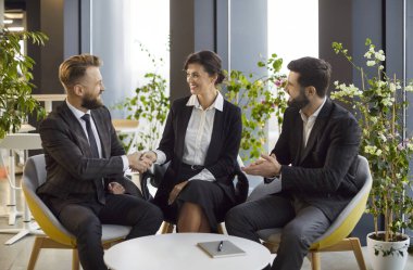 Modern ofiste masada oturan ve anlaşmaya sevinen üç genç iş adamından oluşan bir grup greve gitti. Erkek, kadınla anlaşma imzalarken ya da yeni çalışanı selamlarken tokalaşıyor.