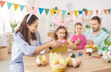 Mutlu aile Paskalya için dekorasyon yapmayı, renkli yumurta süslemeyi, bahar tatili geleneğini, tavşan kulağı takan çocuklarla eğlenceli aktiviteleri, tatil partileri dekorasyonunu, festival atmosferini seviyor.