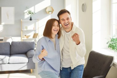 Neşeli genç bir çift, evde durup yeni bir daireye taşınmayı kutlarken ya da birlikte mutlu anların tadını çıkarırken evet jestleri yapıyor. Aşk, duygular ve insanlar kavramı.