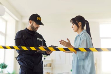 Üniformalı erkek polis memuru endişeli kadın tanık ya da kurbanı sorguluyor ve dinliyor. Polis uyarı bandının yanındaki rapora detayları yazıyor, kanıt topluyor, suçu araştırıyor..