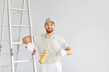 Bir erkek ressam ya da işçi portresi, ev yenileme çalışmaları sırasında olumlu bir jest yapar. Kendine güven ve profesyonellik, bir inşaat projesinde çalışan yetenekli bir işçiyi sergilemek..