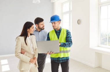 Foreman çalışanı ve aile müşterisi işçi toplantısını denetliyor ve yönetiyor, proje planına bakıyor, planları tutuyor, iş planlıyor, inşaat mühendisiyle mimar sohbeti yapıyor.