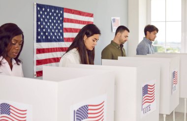 Bir grup mutlu Amerikan vatandaşının portresi. Seçim günü oy verme kabininde oy veren kadın ve erkekler oy kullanma merkezinde duruyor..