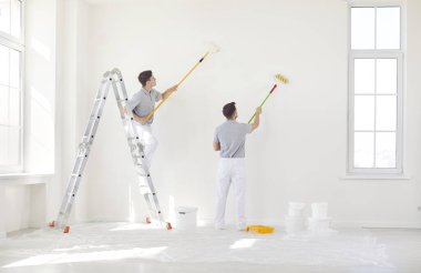 Profesyonel erkek ressamlardan oluşan bir ekip, bir ev ya da ofisteki yenileme sırasında paten fırçasıyla duvar boyamak için birlikte çalışıyor. İnşaat ve yenileme çalışmalarında ortak çaba ve beceri.