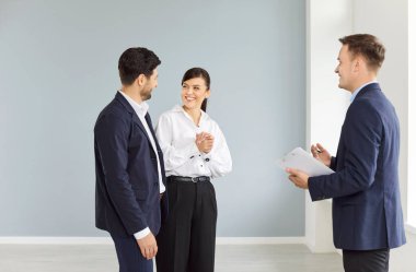 Bir adam ve bir kadın boş bir evde bir ajanla dikiliyorlar, yakın plan. Evli bir çift yeni bir daireyi seviyor, bir menajer evi gezdiriyor. Emlakçılık konsepti, emlakçılık.