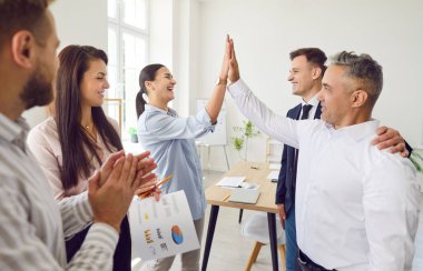 Ofisteki grup toplantısında pozitif iş adamlarından oluşan bir ekip birbirlerine beşlik çakıyor. Profesyonel bir konferans ortamında takım çalışması, birliktelik ve işbirliği.