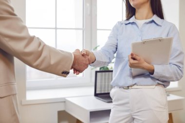 Ofiste erkek iş arkadaşı ya da müşteriyle el sıkışan, anlaşmaya varan, iyi anlaşma yapan, kontrat imzalayan ya da yeni çalışanı selamlayan iş kadınının yakın plan çekimleri. Takım çalışması konsepti