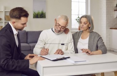 Yaşlı çift müşterileri evde bir emlakçı, finans danışmanı ya da sigorta danışmanı ile sözleşme imzalarlar. Gayrimenkul ve mali meselelerle ilgili anlaşmaları tamamlıyorlar..