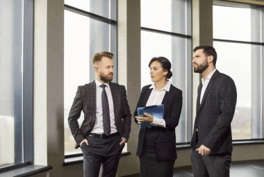 Modern ofis salonunda duran iş adamları, motivasyon ekibi, emlakçı, ipotek ya da kira, mutlu işçiler, sunan, satan, proje detaylarını tartışan iş adamları