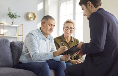 Yaşlı bir çift, finansal danışman, danışman ya da temsilci ile sözleşme imzalıyor. Güven, profesyonellik ve gelecek için güvenli bir ortaklığı yansıtan önemli yatırım kararı.