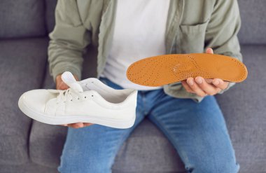 Ayakkabının içine bir insole sokan bir adamı yakından çek. Uygun ayakkabı ve ortopedi ve ortopedi bakımının önemini vurgulayarak, ortopedi veya ayak sağlığıyla ilgili sağlık bilinçli eylem.