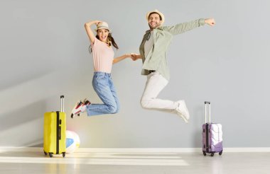 Neşeli atlayışlar, yeni evli çift bavullarını topladılar, yaz plajında tekerlek valizleri, turizmin, yolculuğun, yolculuğun, yolculuğun, yeni evli tatilin, balayı planlama eğlencesinin tadını çıkarmaya hazırlar.