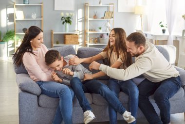 Evde neşeli komik bir aile, ebeveynler ve çocuklar mutlu, mutlu, gıdıklanan bir oğlan çocuğu, hafta sonunu kutluyor, gülümsüyor, eğleniyor, aile toplantısından keyif alıyor, sıcak ilişkiler kuruyor. 