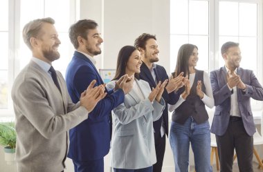 Profesyonel şirket çalışanlarının yan görünüşü, hoparlörden hoparlöre el çırpması. Modern ofiste konferansa, seminere ya da kurumsal eğitime katılan mutlu iş adamları takımı.