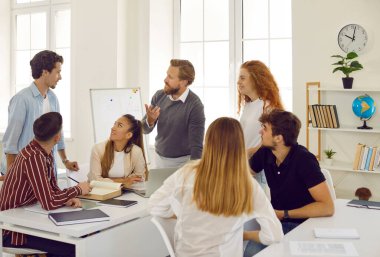 Yaratıcı dost canlısı erkek öğretmen eğitim dersi alan öğrencilerle konuşur ve tartışır. Bir grup üniversite öğrencisi sınıfta olumlu tartışmalar yapıyorlar. Eğitim kavramı.