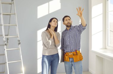 İnşaatçı ya da tamirci, ev sahibiyle bazı değişiklikler hakkında konuşur. Erkek işçi ve genç bir kadın evdeki aydınlık oturma odasında durup bir şeyi işaret ediyor ve süreci anlatıyor.