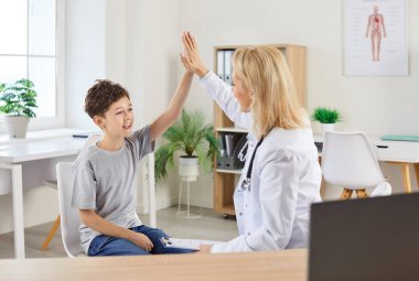 Erkek hasta hastanede tıbbi konsültasyon sırasında bir doktor veya hemşireyle beşlik çakıyor. Bu konuşma, sağlık ekibiyle genç hasta arasında destekleyici bir atmosfer sağlıyor..